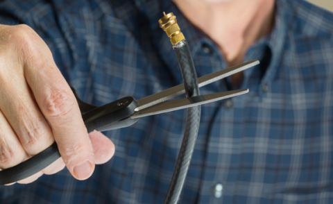 Man in flannel literally cutting a cord with scissors