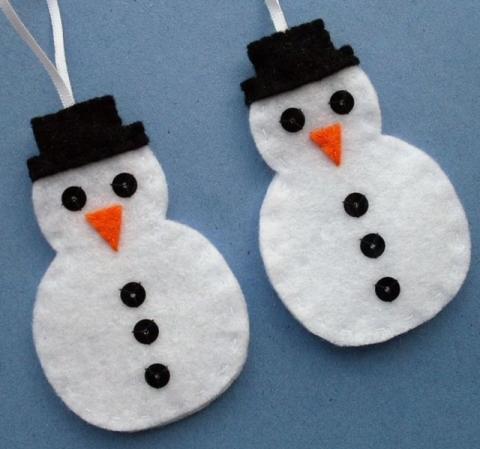 Two simple felt cutout ornaments resembling snowmen with carrot noses and top hats