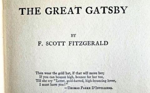 Photograph of the opening page of "The Great Gatsby" by F. Scott Fitzgerald, listing in a black serif font the title, author, and a quote by Thomas Parke D'Invilliers (a pen name of the author), reading "Then wear the gold hat, if that will move her; If you can bounce high, bounce for her too, Till she cry "Lover, gold-hatted, high-bouncing lover, I must have you!""
