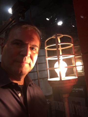 Photograph of programmer Robert Viagas lit by a metal-rimmed historic light in a darkened room