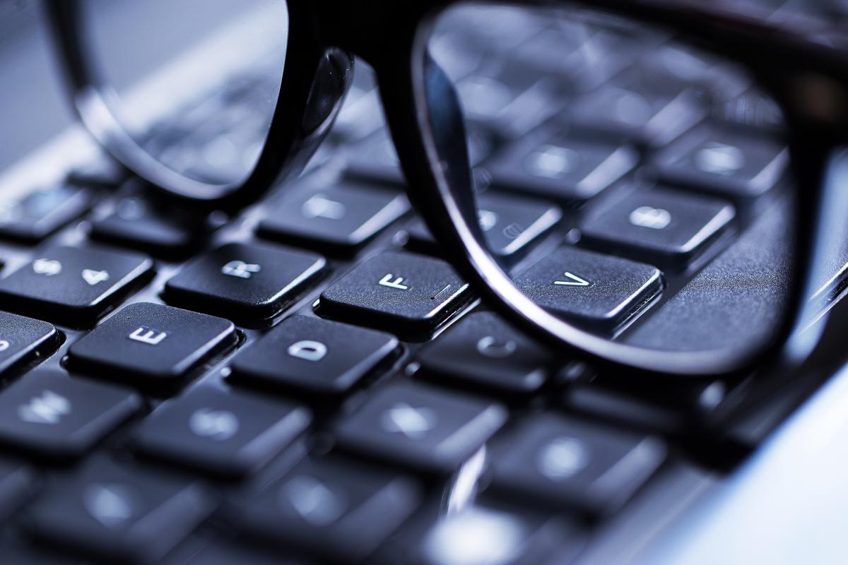 Closeup of keyboard with glasses sitting on top