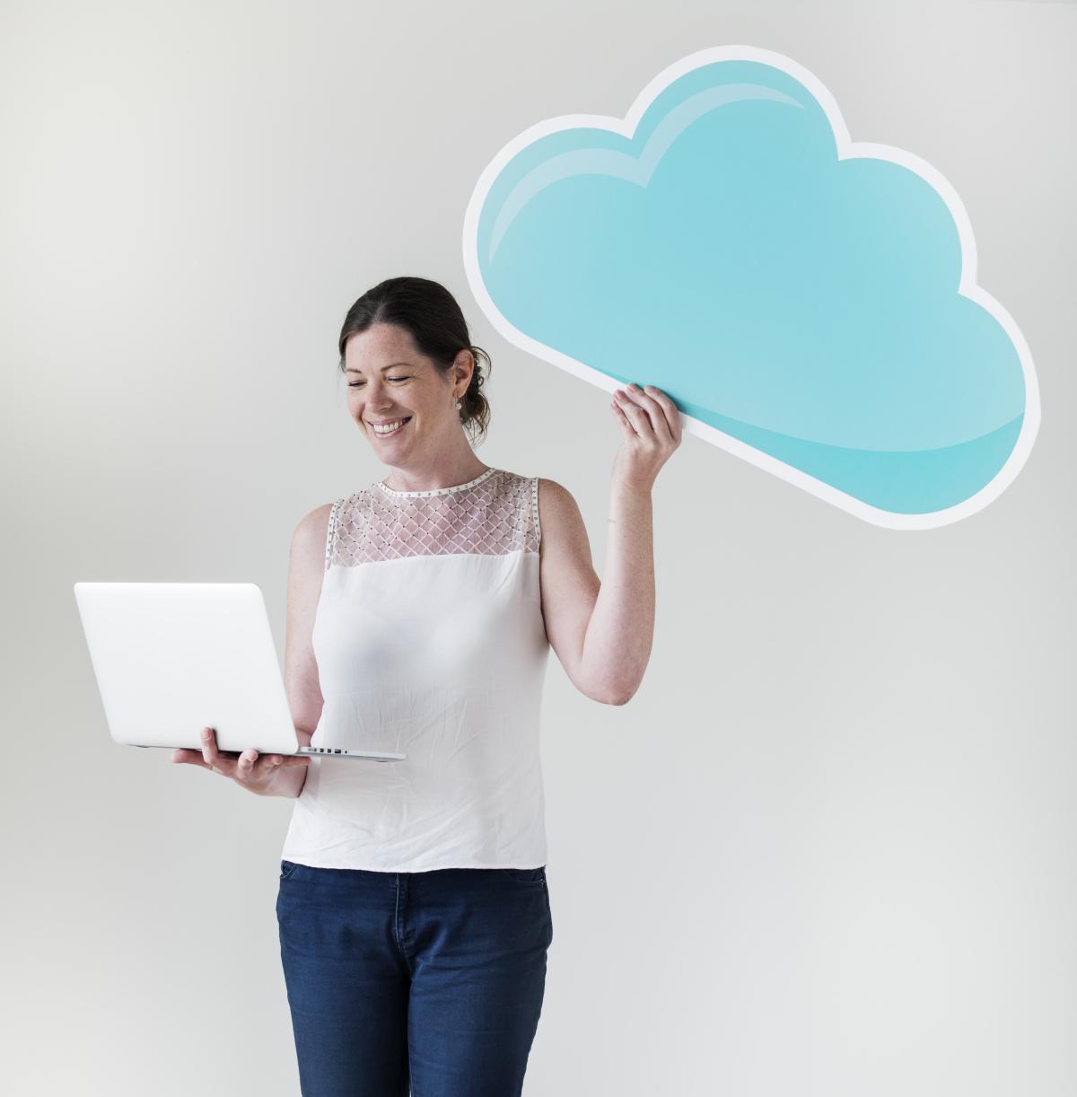 Woman standing holding a laptop in one hand and a stylized blue cloud icon in the other