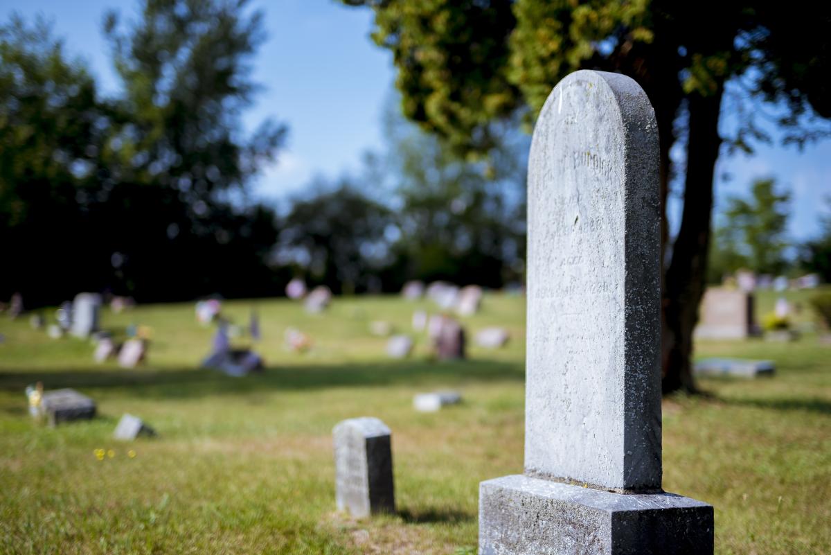 Photograph of a graveyard during a sunny day with one tall round grave in the foreground