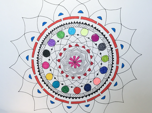 Simple hand-drawn mandala on white paper with partially colored detailing in a rainbow of colors